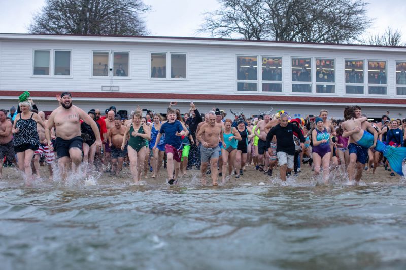 Participants in the 2025 New Year's plunge run into the water at Onset Bay Center.