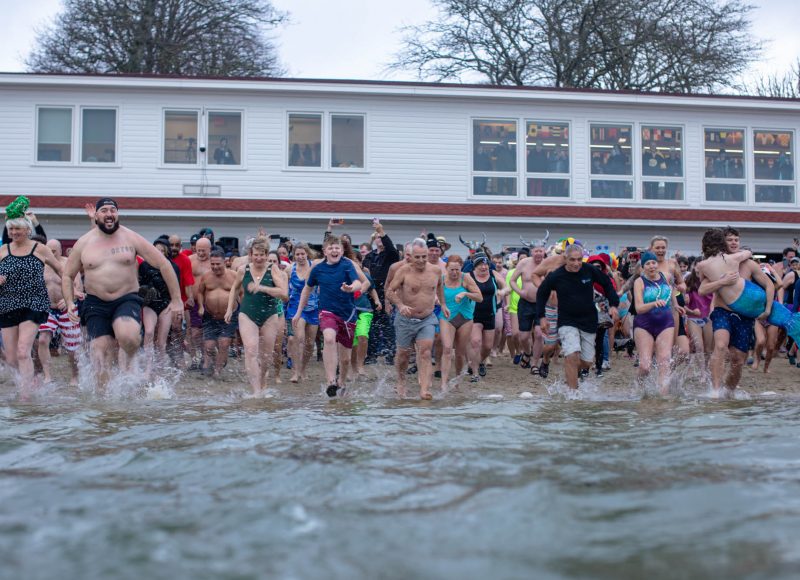 Participants in the 2025 New Year's plunge run into the water at Onset Bay Center.